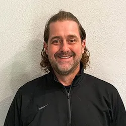 Smiling man wearing a black Nike jacket.
